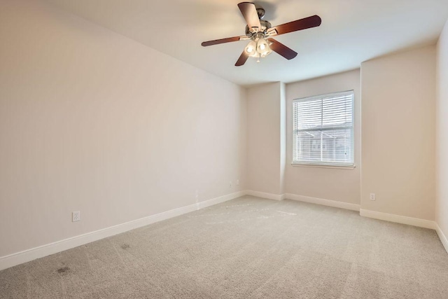 spare room featuring baseboards, a ceiling fan, and light colored carpet