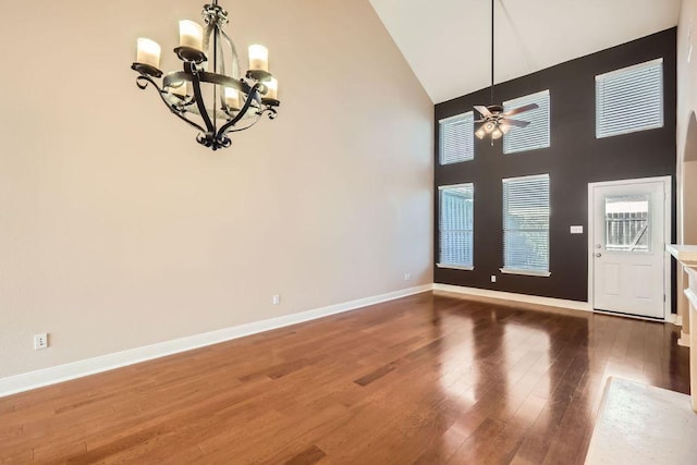 interior space with ceiling fan with notable chandelier, high vaulted ceiling, wood finished floors, and baseboards