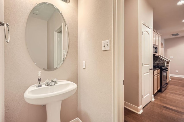 bathroom with visible vents, baseboards, and wood finished floors