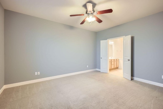 unfurnished bedroom with light carpet, connected bathroom, baseboards, and ceiling fan