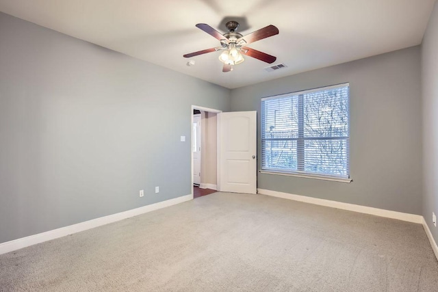 carpeted empty room with visible vents, ceiling fan, and baseboards