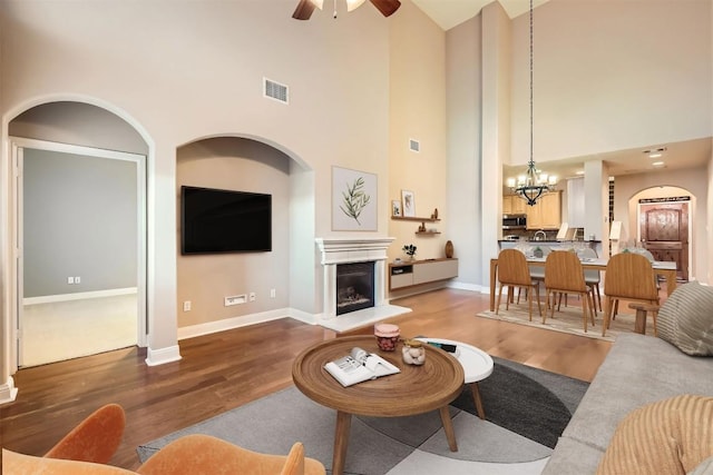 2210 Onion Creek Pkwy Unit 503, Austin, TX 78747 - living area with a high ceiling, a chandelier, wood finished floors, ceiling fan, and a fireplace with raised hearth