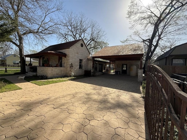 401 San Jacinto St, Smithville, TX 78957 - view of side of property featuring stone siding, an attached carport, driveway, and fence