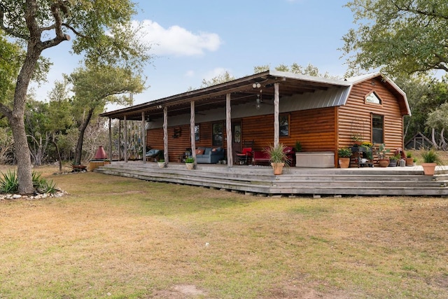 back of house featuring faux log siding, a lawn, a wooden deck, and a gambrel roof