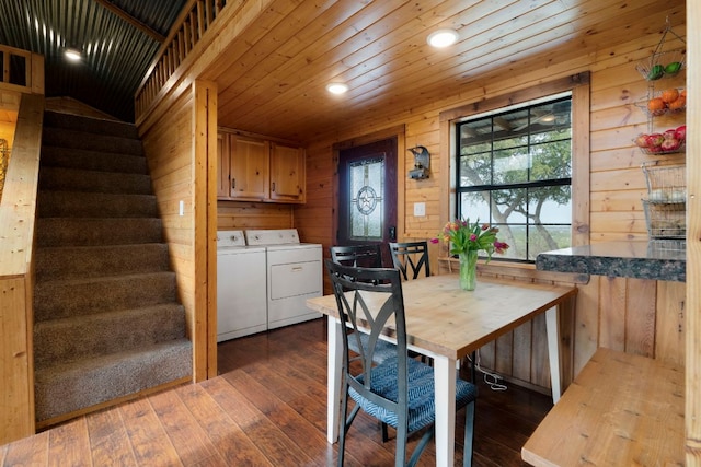 dining room featuring dark wood-type flooring, wooden walls, wooden ceiling, independent washer and dryer, and stairs