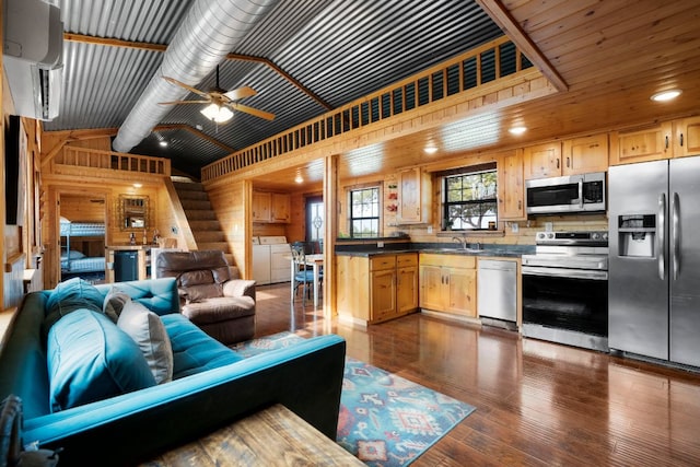 living area featuring ceiling fan, vaulted ceiling, dark wood-type flooring, and washer and dryer