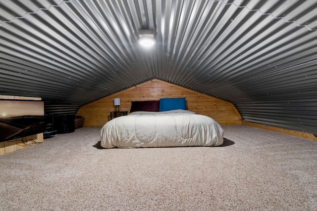 carpeted bedroom featuring lofted ceiling and wood walls