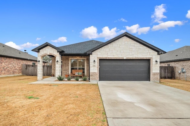 view of front of home with brick siding, concrete driveway, a front yard, fence, and a garage