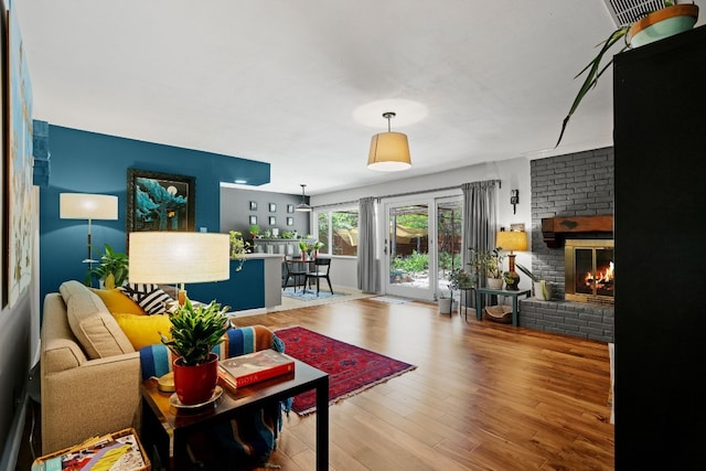 living area with visible vents, a fireplace, and wood finished floors