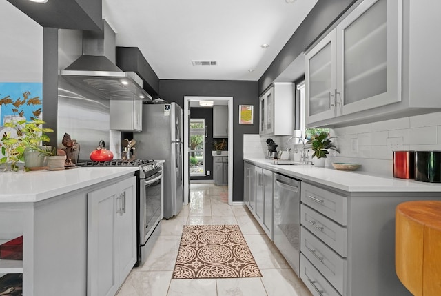 kitchen with a sink, visible vents, appliances with stainless steel finishes, wall chimney exhaust hood, and tasteful backsplash