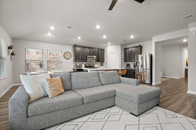 living area featuring light wood finished floors, baseboards, visible vents, and recessed lighting