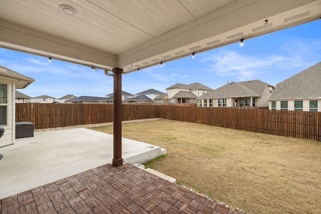 view of yard with a patio area, a fenced backyard, and a residential view