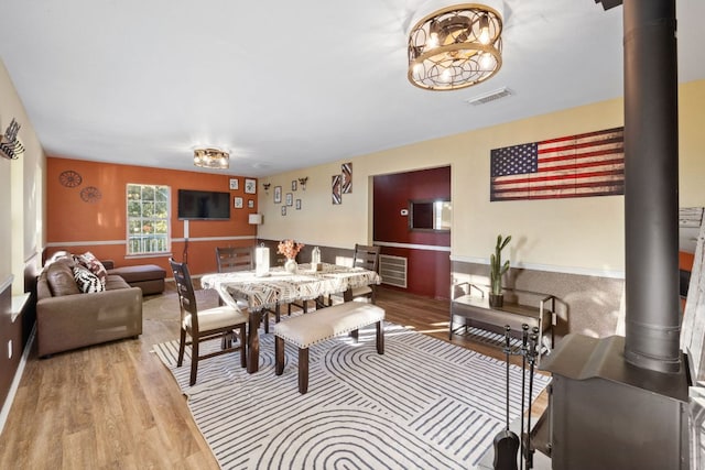 dining space featuring visible vents, wood finished floors, and a wood stove