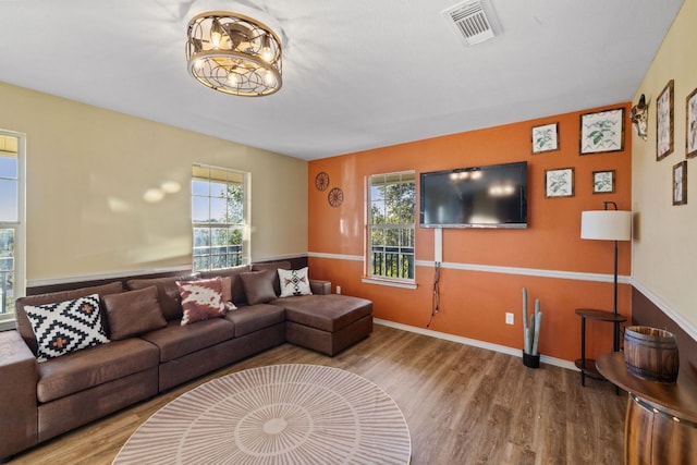 living area with baseboards, visible vents, and wood finished floors