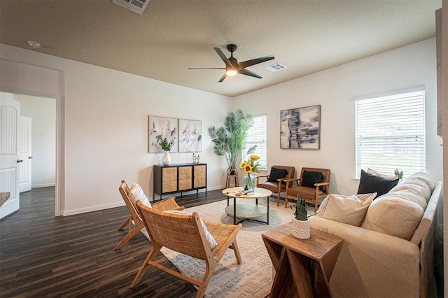 living room featuring a ceiling fan, visible vents, baseboards, and wood finished floors