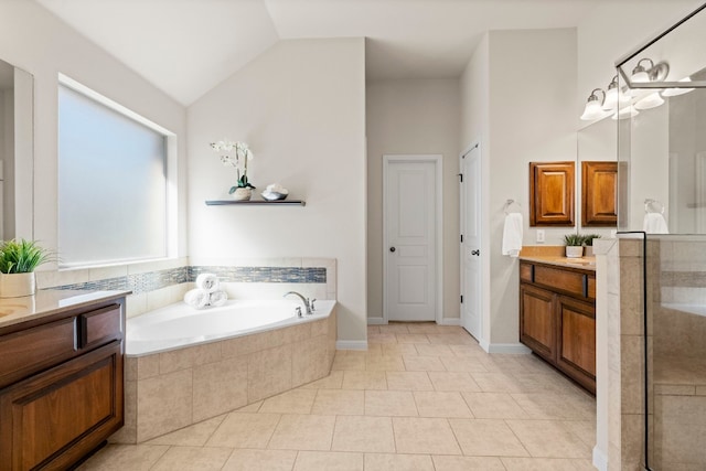 full bathroom featuring a garden tub, vaulted ceiling, two vanities, and tile patterned floors