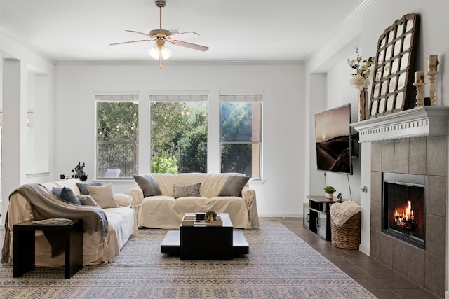 living area featuring crown molding, a fireplace, baseboards, and a ceiling fan