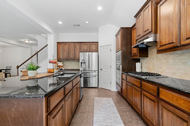 kitchen featuring under cabinet range hood, a sink, visible vents, appliances with stainless steel finishes, and dark stone countertops