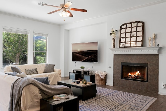 living room with baseboards, visible vents, a ceiling fan, crown molding, and a fireplace