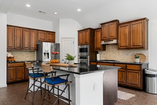 kitchen with a center island, stainless steel appliances, visible vents, vaulted ceiling, and under cabinet range hood