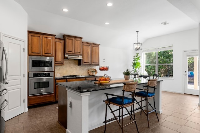 kitchen featuring visible vents, brown cabinets, stainless steel appliances, under cabinet range hood, and backsplash