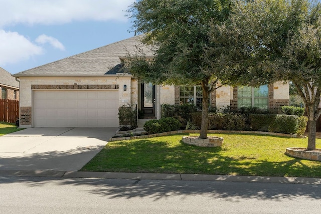 view of property hidden behind natural elements with brick siding, roof with shingles, concrete driveway, a garage, and a front lawn