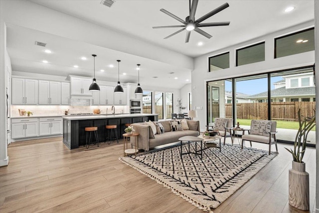 living area with light wood finished floors, visible vents, a ceiling fan, and recessed lighting