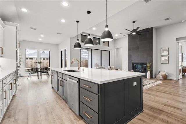 kitchen with a tiled fireplace, white cabinets, a sink, and light countertops