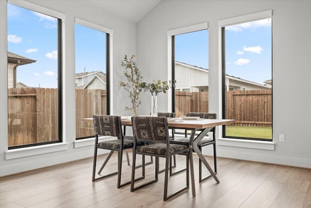 dining area featuring lofted ceiling, baseboards, and wood finished floors