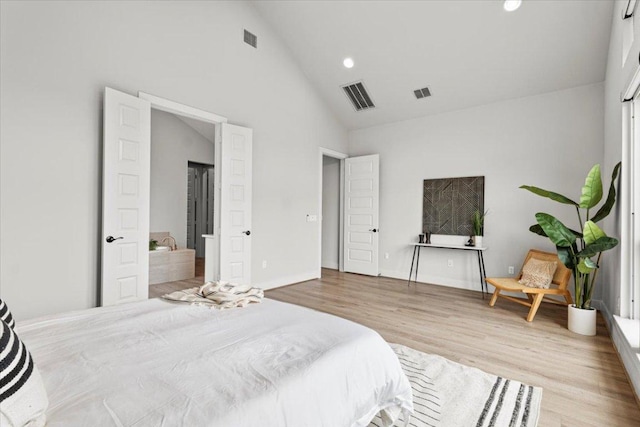 bedroom with high vaulted ceiling, visible vents, and wood finished floors