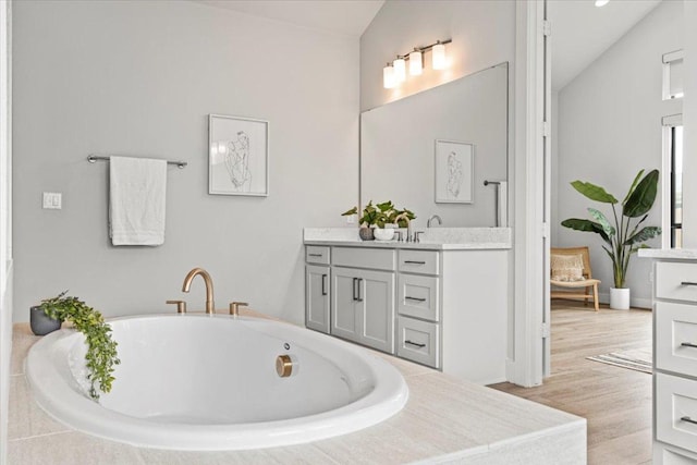 full bath with lofted ceiling, a freestanding tub, and vanity