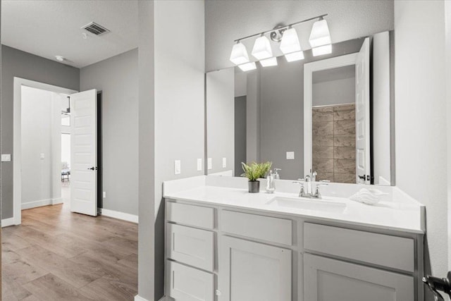 bathroom with visible vents, vanity, baseboards, and wood finished floors