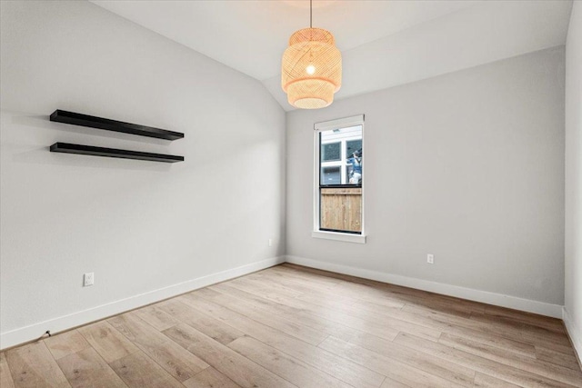 unfurnished room with lofted ceiling, baseboards, and wood finished floors