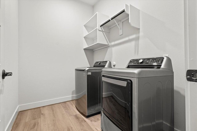 laundry room with baseboards, laundry area, washer and clothes dryer, and light wood-style floors