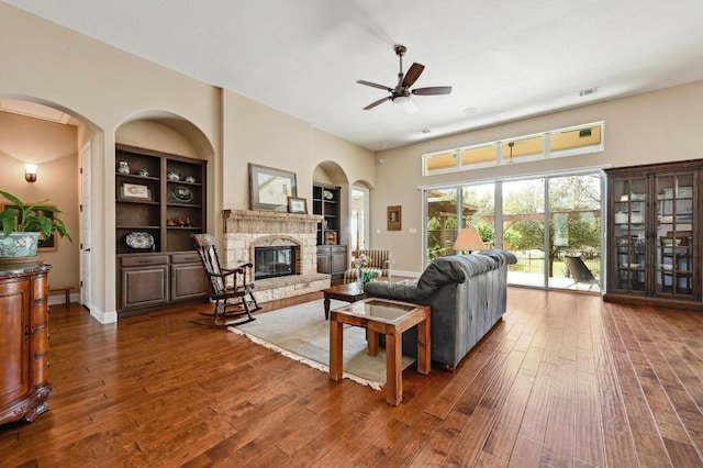 114 Hazelnut Ct, Driftwood, TX 78619 - living area featuring a ceiling fan, hardwood / wood-style flooring, a glass covered fireplace, and built in shelves