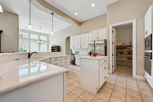 114 Hazelnut Ct, Driftwood, TX 78619 - kitchen featuring a sink, stainless steel appliances, a center island, decorative light fixtures, and arched walkways