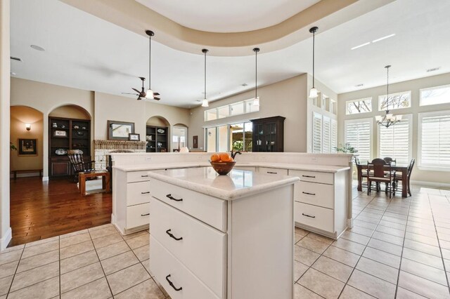 114 Hazelnut Ct, Driftwood, TX 78619 - kitchen featuring a kitchen island, light tile patterned flooring, arched walkways, a chandelier, and a ceiling fan