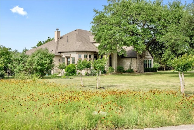 114 Hazelnut Ct, Driftwood, TX 78619 - view of front facade with a front yard, a chimney, and stone siding