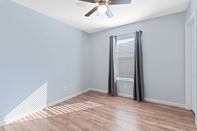 spare room with a ceiling fan, light wood-style flooring, and baseboards