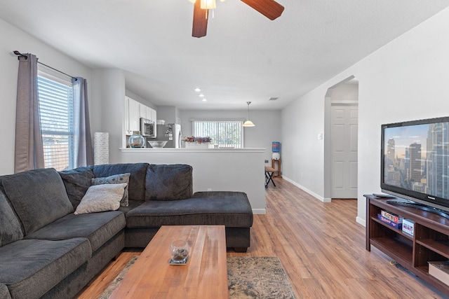 living room featuring a healthy amount of sunlight, light wood-style flooring, baseboards, and ceiling fan