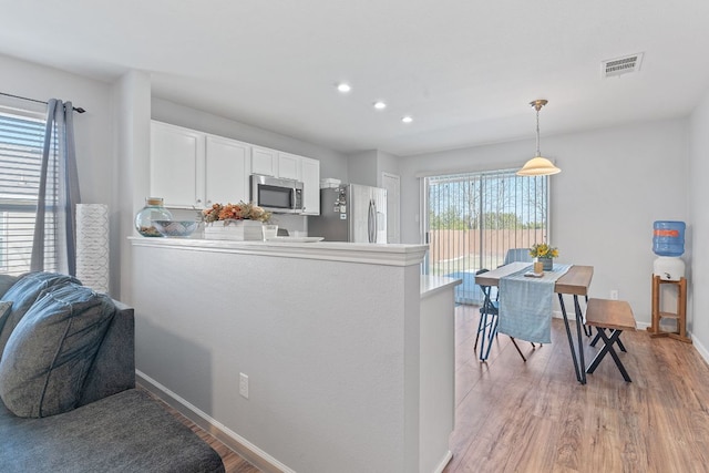 kitchen featuring stainless steel appliances, visible vents, light wood-style floors, white cabinetry, and baseboards