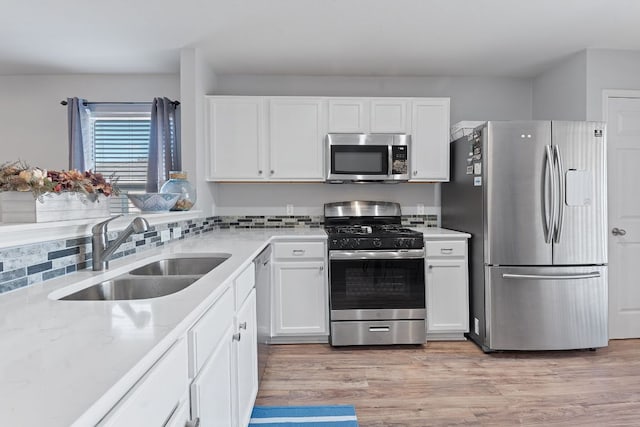 kitchen with a sink, light wood-style flooring, white cabinetry, and stainless steel appliances