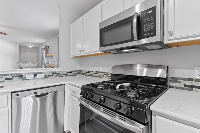 kitchen with tasteful backsplash, light stone counters, white cabinets, and stainless steel appliances