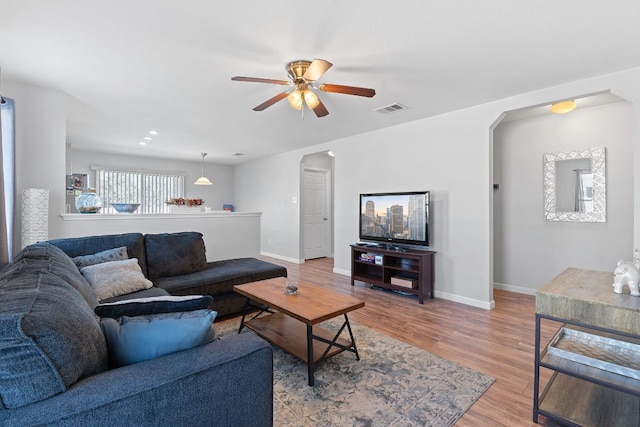 living room with baseboards, visible vents, arched walkways, and wood finished floors