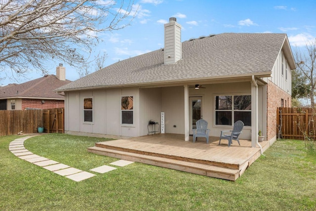 back of house with a lawn, a fenced backyard, a chimney, roof with shingles, and a wooden deck