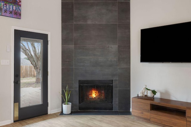 unfurnished living room featuring baseboards, a tiled fireplace, and wood finished floors