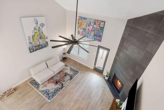 living room featuring a large fireplace, baseboards, and wood finished floors