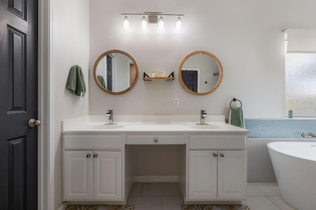 bathroom featuring a freestanding bath, double vanity, a sink, and tile patterned floors