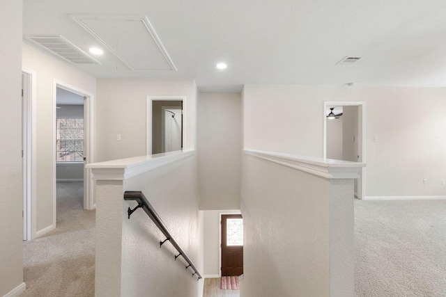 corridor with light colored carpet, visible vents, an upstairs landing, a wealth of natural light, and attic access