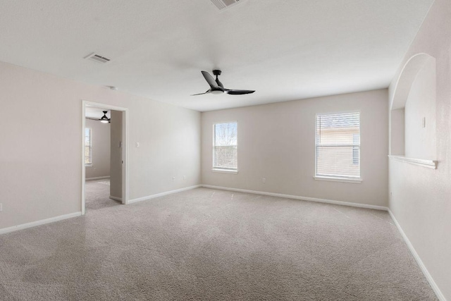 carpeted empty room with baseboards, visible vents, and a ceiling fan